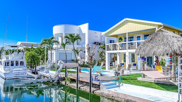 rear view of house featuring a water view, a balcony, and a swimming pool