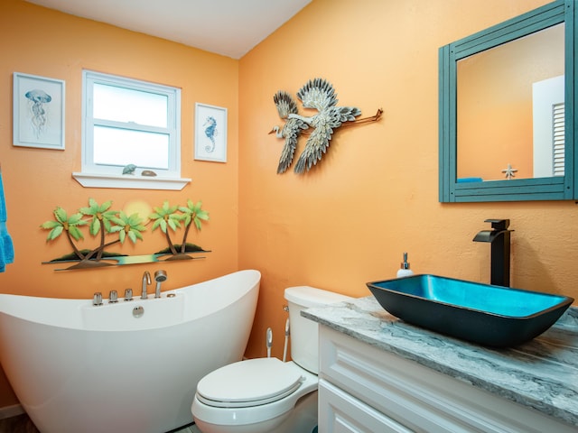 bathroom with vanity, a tub to relax in, and toilet