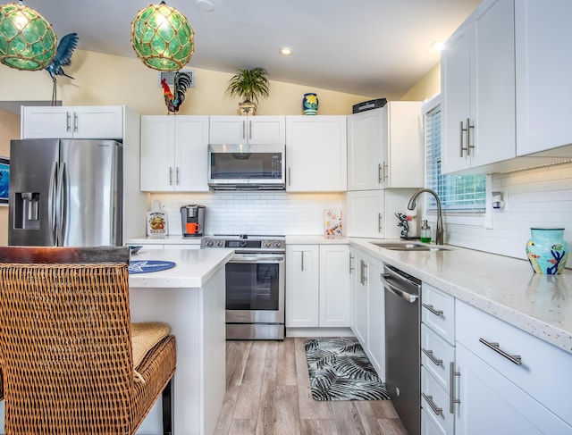 kitchen featuring lofted ceiling, sink, white cabinets, light hardwood / wood-style floors, and stainless steel appliances