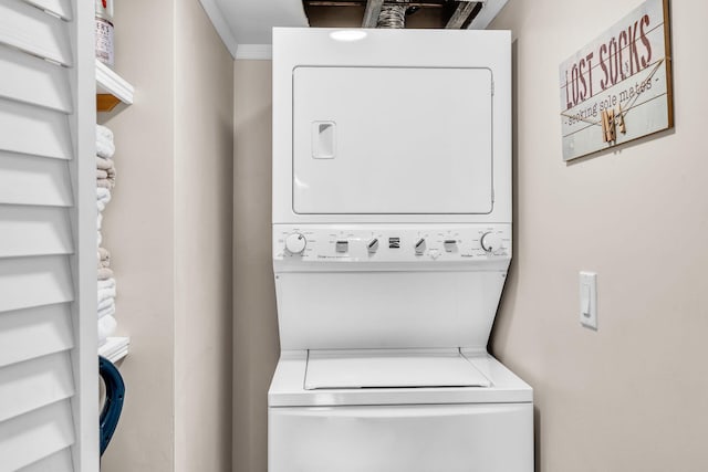 washroom with ornamental molding and stacked washer and clothes dryer