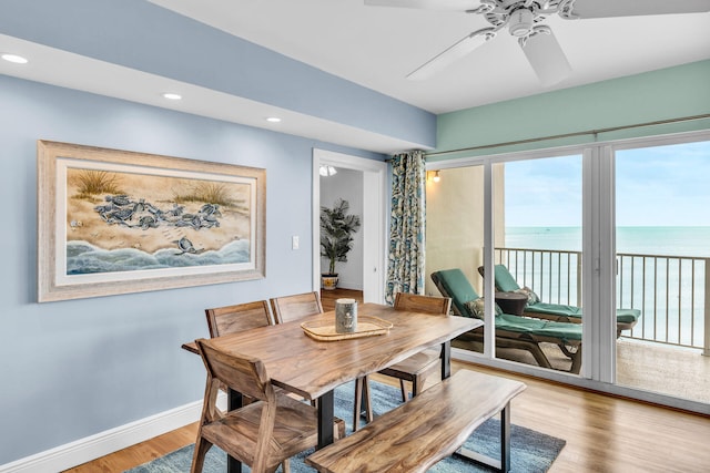 dining room featuring wood-type flooring, a water view, and ceiling fan