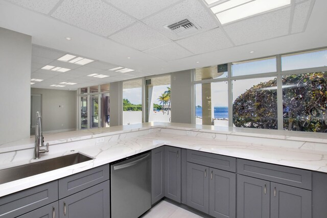 kitchen featuring sink, gray cabinetry, stainless steel dishwasher, light stone counters, and a water view