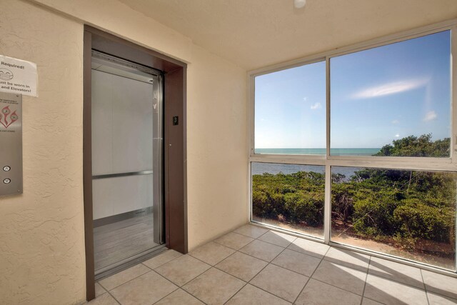 unfurnished sunroom with a water view and elevator