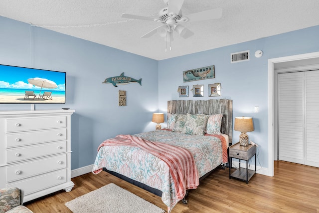 bedroom with ceiling fan, light hardwood / wood-style flooring, and a textured ceiling