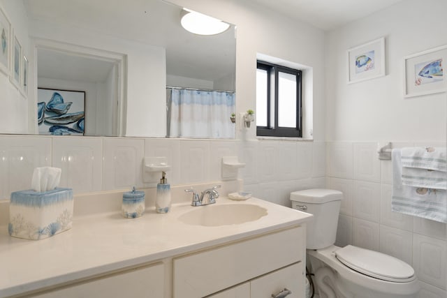 bathroom featuring vanity, tile walls, and toilet