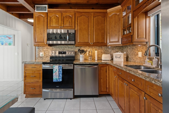 kitchen featuring sink, light tile patterned floors, appliances with stainless steel finishes, backsplash, and light stone countertops