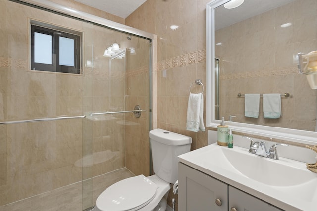 bathroom with vanity, toilet, a shower with door, and tile walls