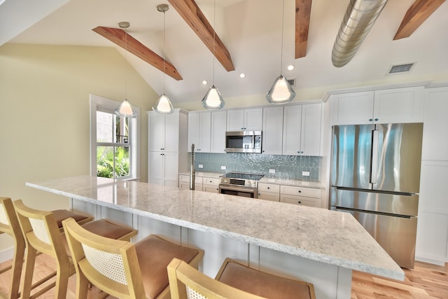 kitchen featuring appliances with stainless steel finishes, a breakfast bar, decorative light fixtures, white cabinets, and decorative backsplash