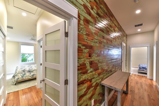 hall featuring light wood-type flooring and brick wall