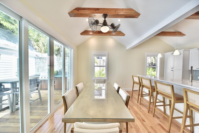 dining space featuring vaulted ceiling with beams and light hardwood / wood-style flooring