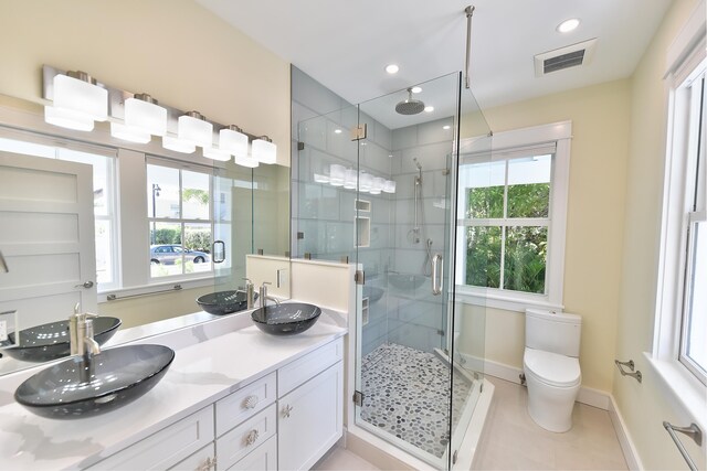 bathroom with tile patterned floors, vanity, toilet, and an enclosed shower