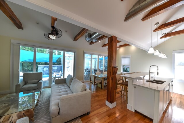 living room with light hardwood / wood-style flooring, sink, vaulted ceiling with beams, and french doors