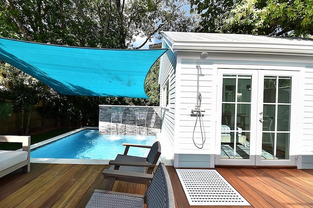 view of pool with french doors, pool water feature, and a wooden deck