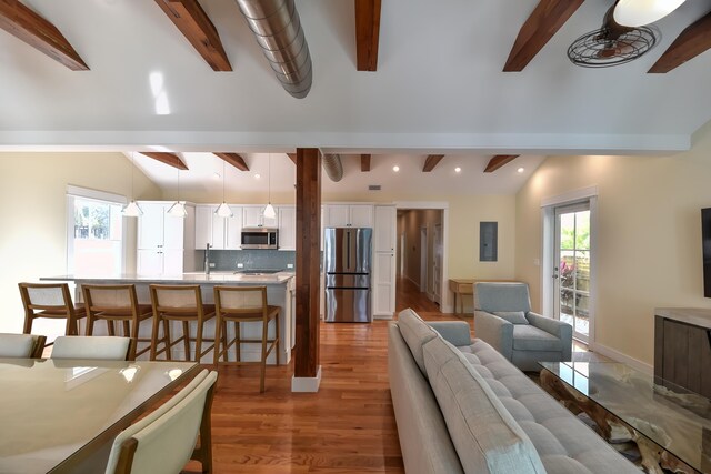 living room with vaulted ceiling with beams, hardwood / wood-style flooring, sink, and ceiling fan