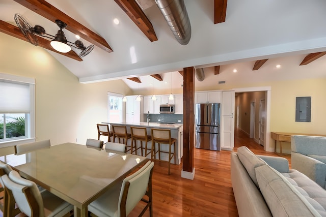 dining area featuring sink, ceiling fan, vaulted ceiling with beams, electric panel, and light hardwood / wood-style floors