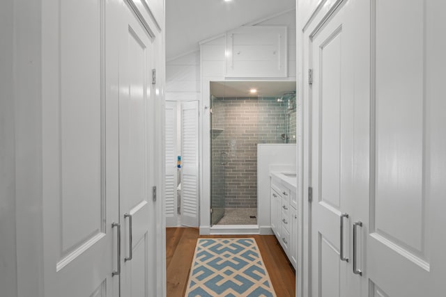 bathroom with vaulted ceiling, a stall shower, wood finished floors, and vanity