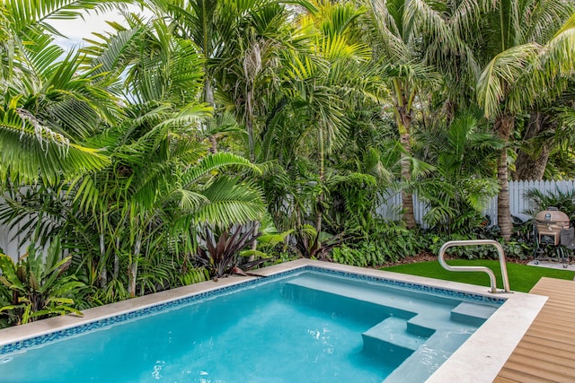 view of swimming pool with a hot tub and fence