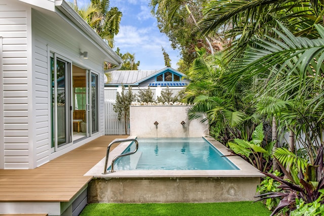 view of pool with a jacuzzi, fence, and a wooden deck