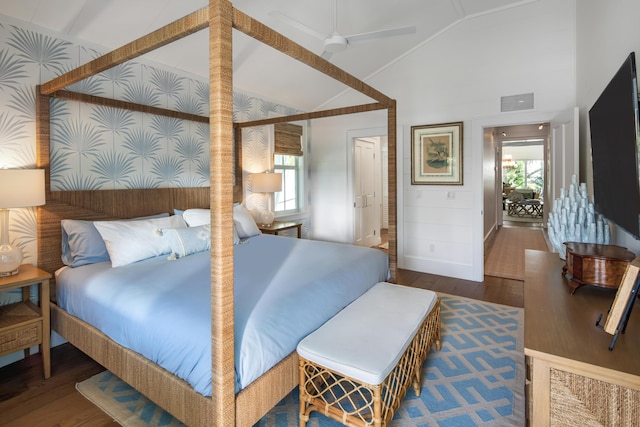 bedroom featuring lofted ceiling, visible vents, wood finished floors, baseboards, and wallpapered walls