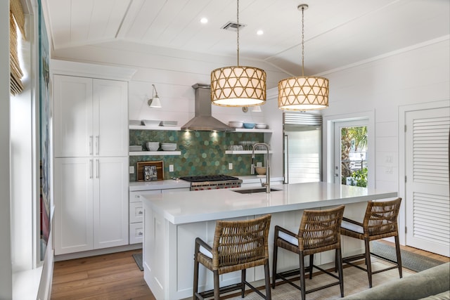 kitchen featuring visible vents, island range hood, vaulted ceiling, a sink, and built in fridge