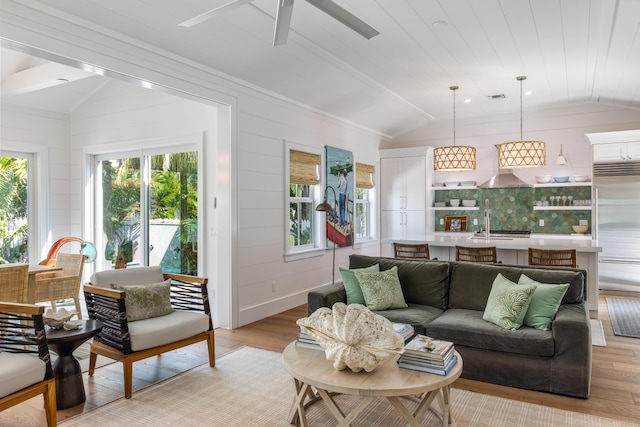 living room with a ceiling fan, lofted ceiling, visible vents, and light wood-style flooring