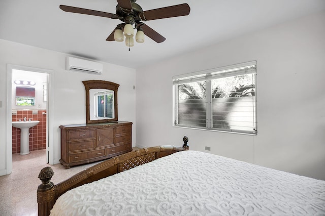 bedroom featuring sink, a wall mounted AC, tile walls, ceiling fan, and ensuite bath