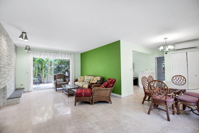 living room featuring a wall mounted air conditioner, a fireplace, washer / clothes dryer, and a chandelier