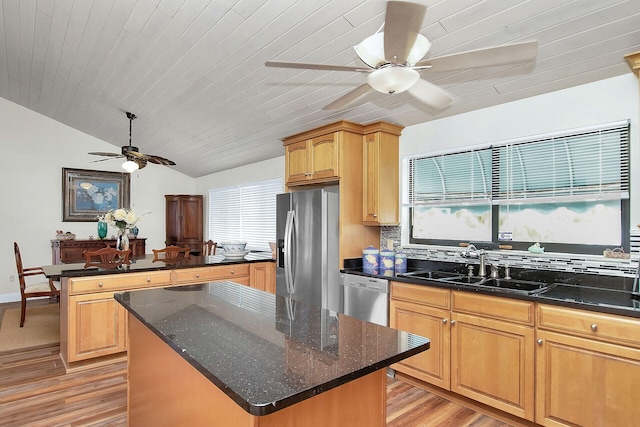 kitchen featuring vaulted ceiling, stainless steel appliances, sink, and a kitchen island