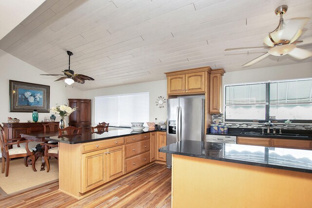 kitchen with lofted ceiling, sink, stainless steel fridge, ceiling fan, and light wood-type flooring