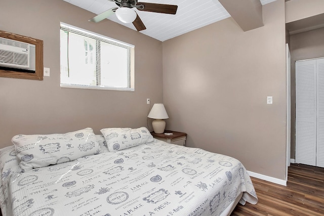 bedroom featuring a wall mounted AC, ceiling fan, dark wood-type flooring, beam ceiling, and a closet