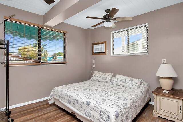 bedroom with dark wood-type flooring, ceiling fan, a wall unit AC, and beamed ceiling