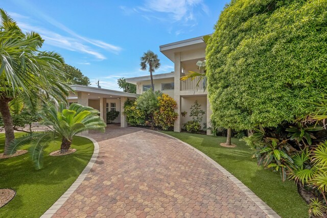 view of front of property with a carport, a balcony, and a front yard