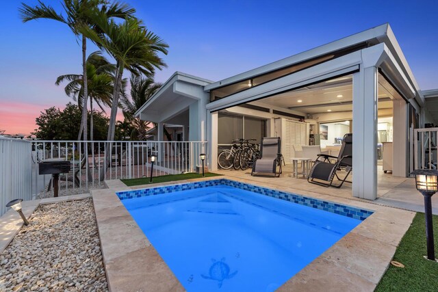 pool at dusk featuring a patio area