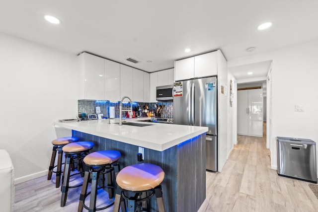 kitchen featuring appliances with stainless steel finishes, white cabinets, a kitchen breakfast bar, and kitchen peninsula