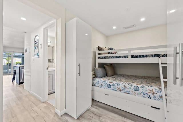 bedroom with connected bathroom, sink, and light wood-type flooring