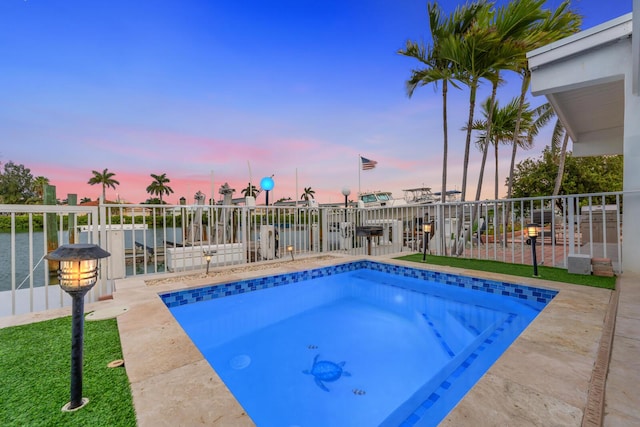 pool at dusk with a patio and a water view