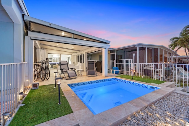 pool at dusk with a yard, a jacuzzi, and a sunroom