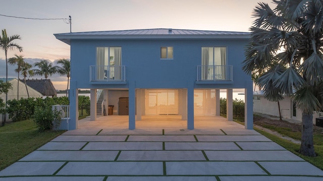 back house at dusk featuring a carport and a balcony