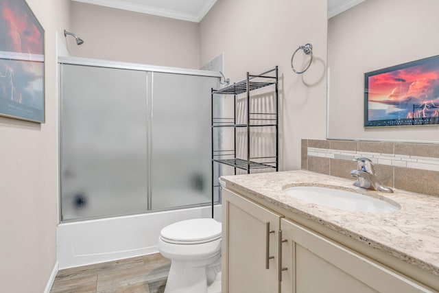 bathroom featuring vanity, wood finished floors, crown molding, toilet, and combined bath / shower with glass door