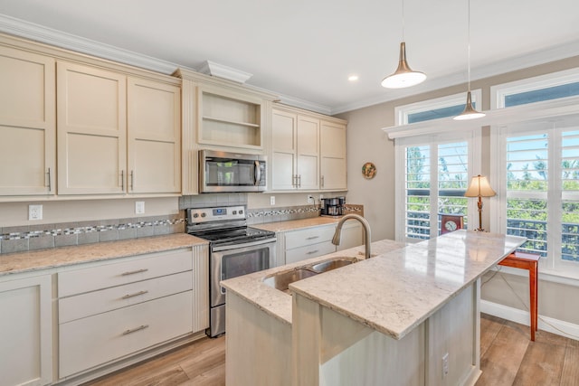 kitchen featuring cream cabinets, ornamental molding, appliances with stainless steel finishes, and a sink