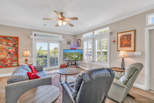 living area with a healthy amount of sunlight, light wood finished floors, and ornamental molding