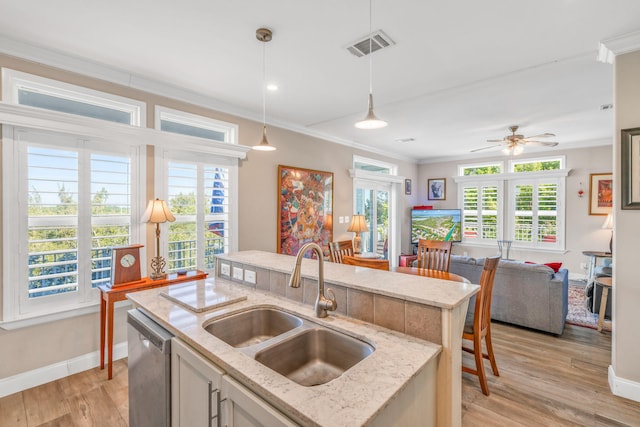 kitchen featuring a sink, open floor plan, crown molding, light wood finished floors, and dishwasher