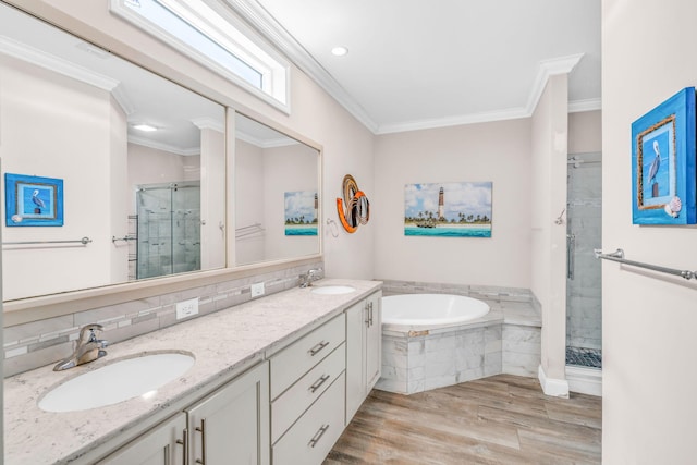 bathroom featuring ornamental molding, a bath, a stall shower, and a sink