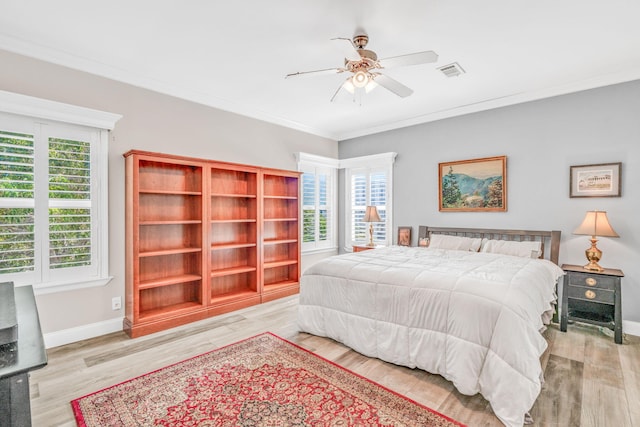 bedroom featuring a ceiling fan, wood finished floors, visible vents, baseboards, and crown molding