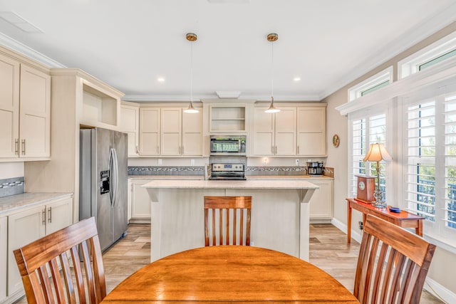 kitchen with cream cabinets, a center island, stainless steel appliances, crown molding, and light wood finished floors