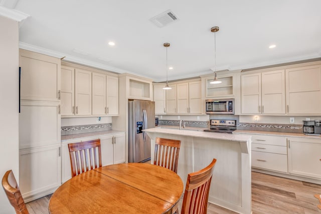 kitchen featuring visible vents, cream cabinets, stainless steel appliances, and light wood-style floors