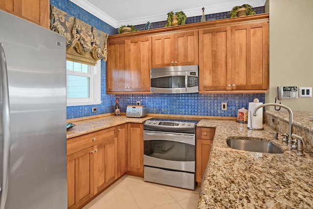 kitchen featuring light stone counters, ornamental molding, appliances with stainless steel finishes, and sink