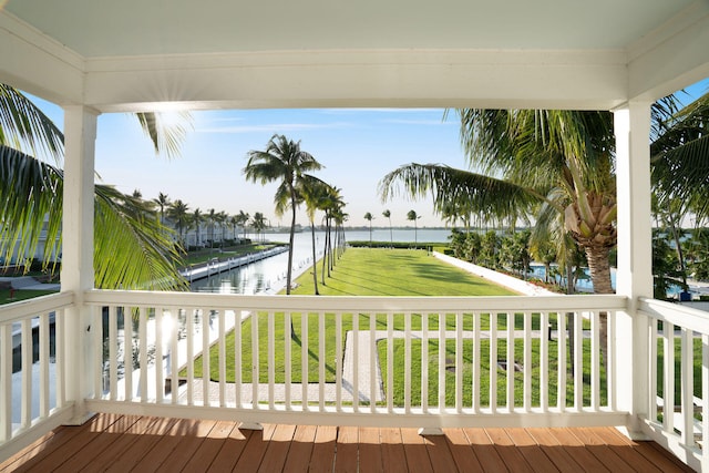 wooden terrace featuring a water view and a lawn