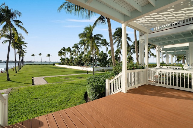 wooden deck featuring a water view, a pergola, and a lawn