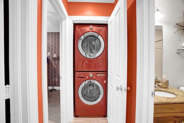 laundry area featuring stacked washer / dryer, sink, and light tile patterned floors